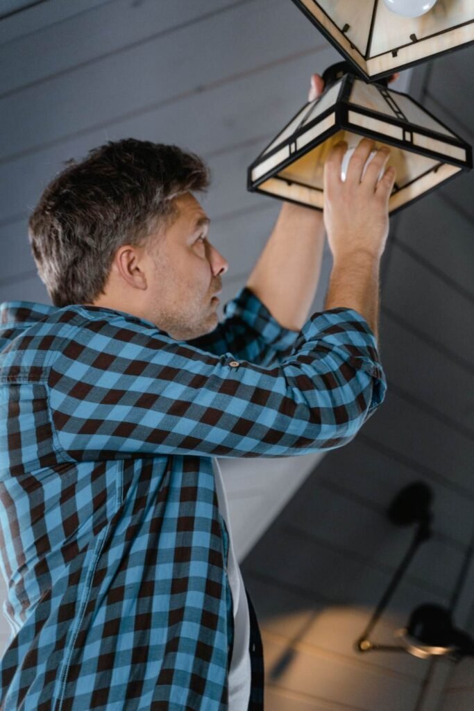 Electrician installing a geometric pendant light fixture for residential lighting in West Palm Beach, FL