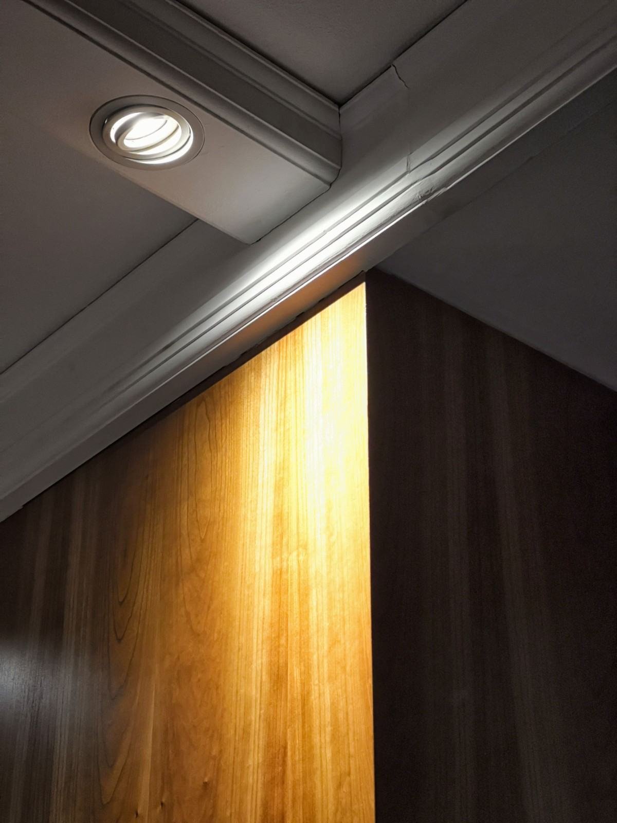 Recessed ceiling light illuminating a wooden wall panel in West Palm Beach, FL